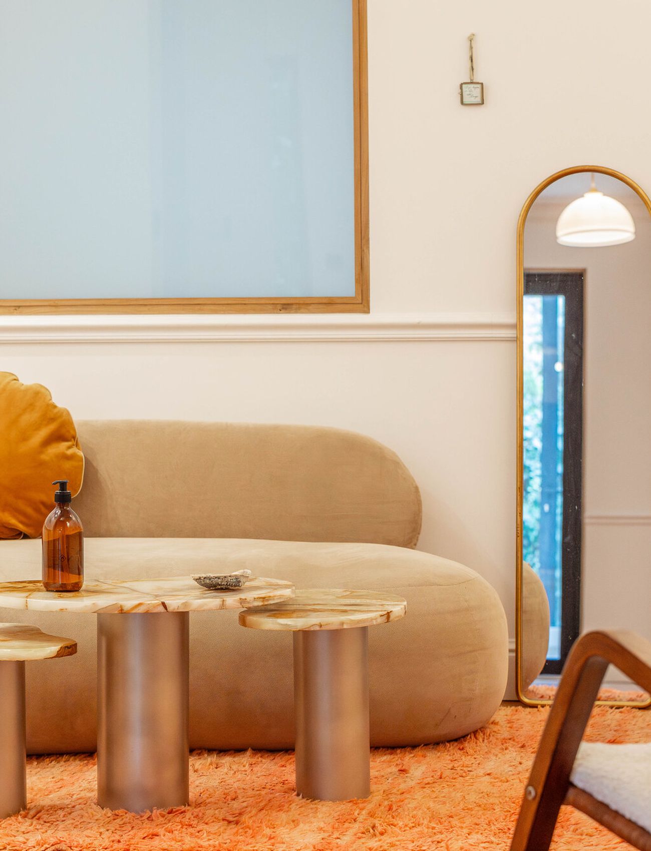 Le salon de Maison Ose : canapé de bouclé, miroir cintré, tapis orangé.